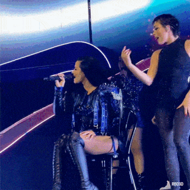 a woman sitting on a chair singing into a microphone with rbd3d written on the bottom