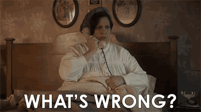a woman sitting on a bed talking on a phone with the words " what 's wrong " above her