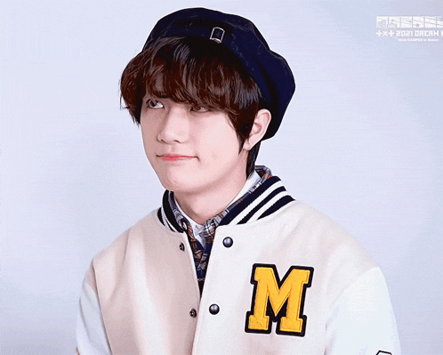 a young man wearing a beret and a jacket with the letter m on it