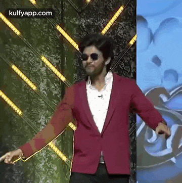 a man wearing a red jacket and sunglasses is standing on a stage .