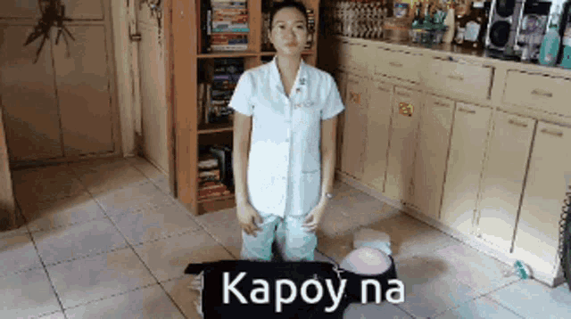a woman in a white coat stands in front of a black bag that says karoy na