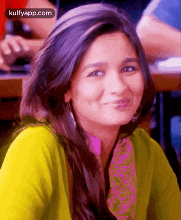 a close up of a woman 's face smiling while wearing a green sweater .