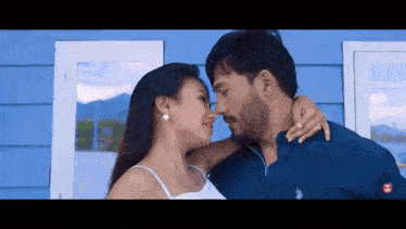 a man and woman are kissing in front of a blue house .