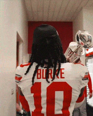 a football player wearing a number 10 jersey is carrying two trophies