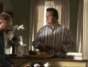 a man in a striped shirt sits at a counter with a plate of fruit on it