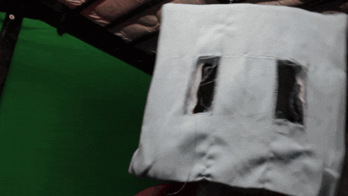 a piece of white cloth with two holes in it against a green background