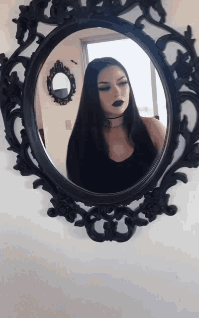 a woman taking a picture of herself in a black mirror