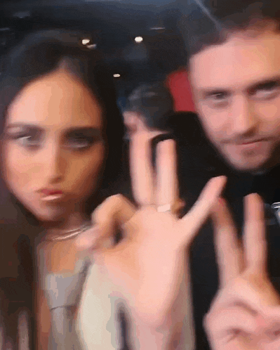 a man and a woman are making peace signs