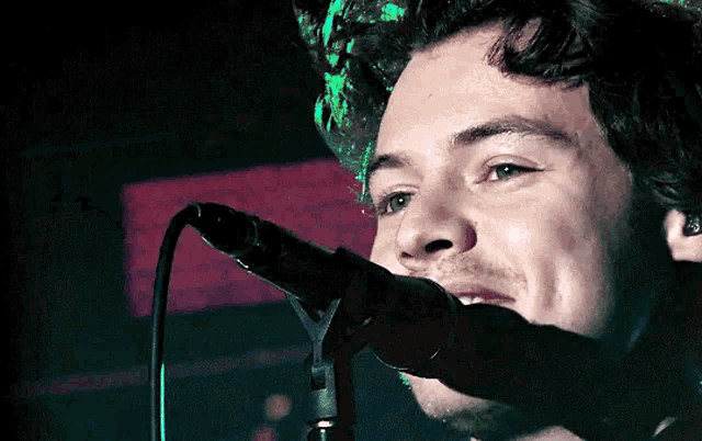 a man singing into a microphone with a green light behind him