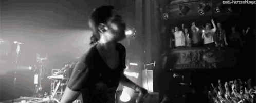 a man is singing into a microphone on a stage while a crowd watches .