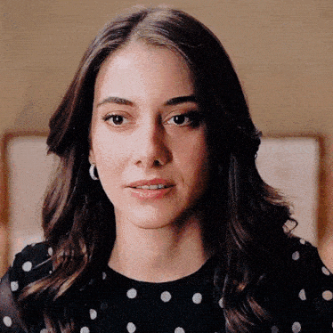 a close up of a woman 's face wearing a black polka dot top