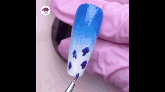 a close up of a person 's hand holding a nail with a blue and white design on it .