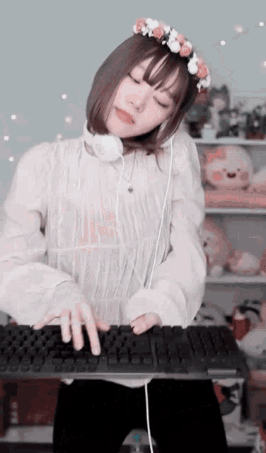 a girl wearing headphones and a flower crown is typing on a keyboard .