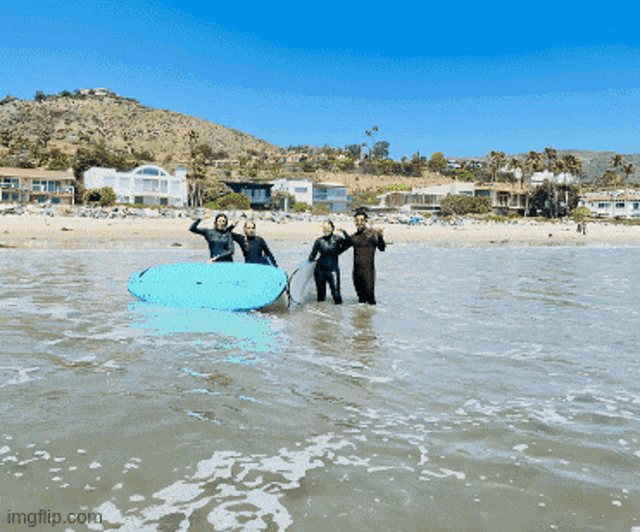 a group of people holding surfboards in the water with imgflip.com in the corner