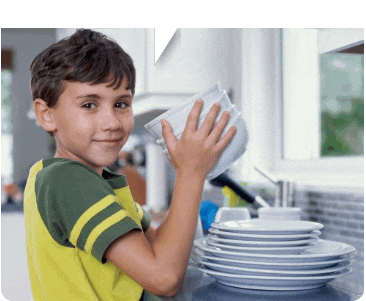 a young boy in a yellow shirt is washing dishes