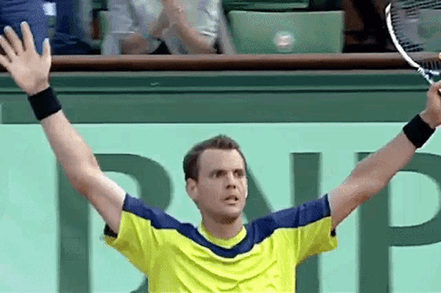 a man in a yellow shirt is holding a tennis racquet in his hand