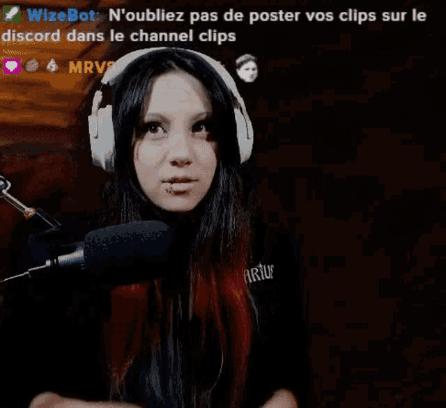 a woman wearing headphones is giving the middle finger while standing in front of a microphone .