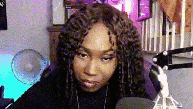 a woman with dreadlocks is sitting in front of a microphone in a recording studio .