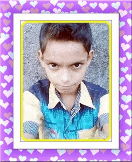 a young boy is taking a picture of himself in a purple frame with hearts on it .
