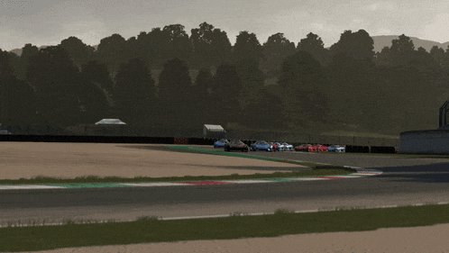 a row of cars are parked on a race track with trees in the background