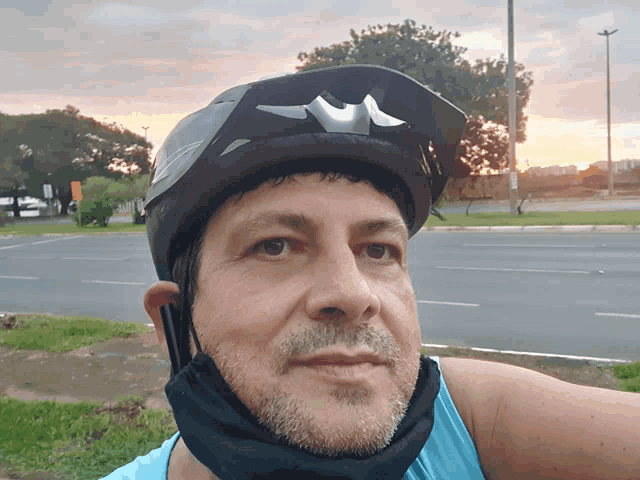 a man wearing a helmet and sunglasses looks at the camera with a sunset in the background