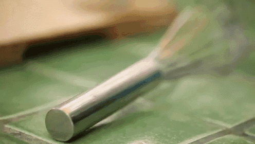 a close up of a stainless steel knife on a green tile counter .