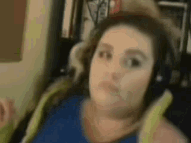a woman is wearing headphones and making a funny face while sitting in a chair .