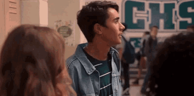 a boy and a girl are standing next to each other in a hallway in front of a sign that says chs .