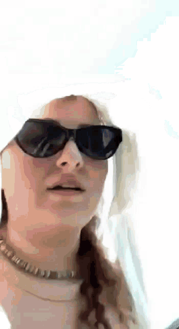 a woman wearing sunglasses and a hat is making a face .