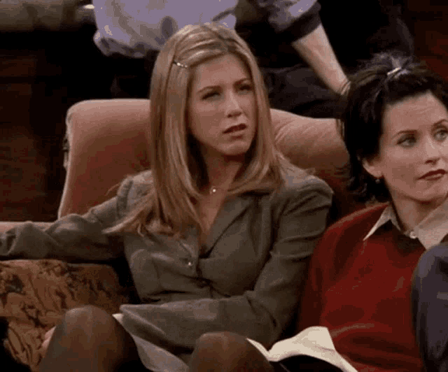 a woman is sitting on a couch with a book in her hand .