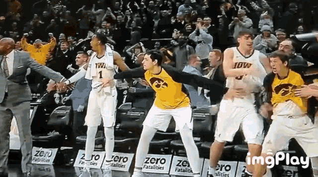 a group of iowa basketball players are dancing on the court in front of a crowd