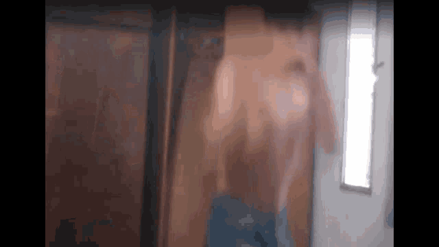 a man without a shirt is standing in front of a wooden door .