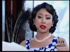 a woman wearing a blue and white dress and a pearl necklace .