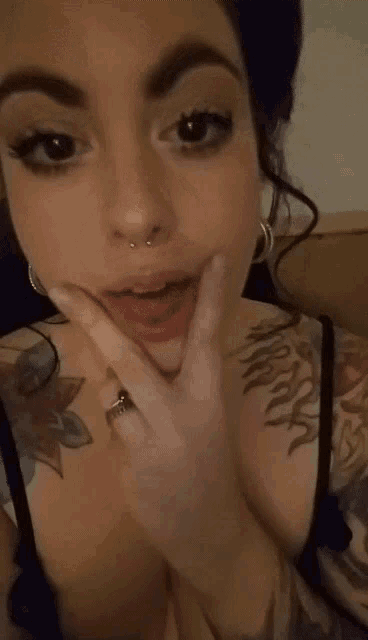 a close up of a woman 's face with a tattoo on her chest