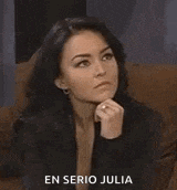 a woman is sitting on a couch with her hand on her chin and a serious look on her face .