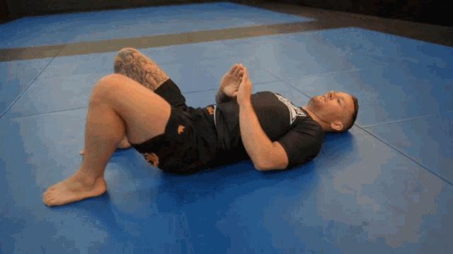 a man is laying on his back on a blue mat with a shirt that has the word tiger on it