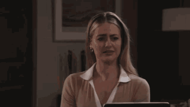 a woman is sitting in front of a laptop computer and making a sad face