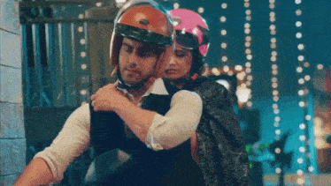 a man is carrying a woman on his back who is wearing a pink helmet .