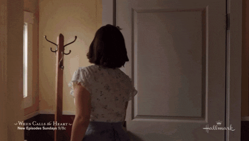 a little girl is standing in front of a door that says hallmark on it