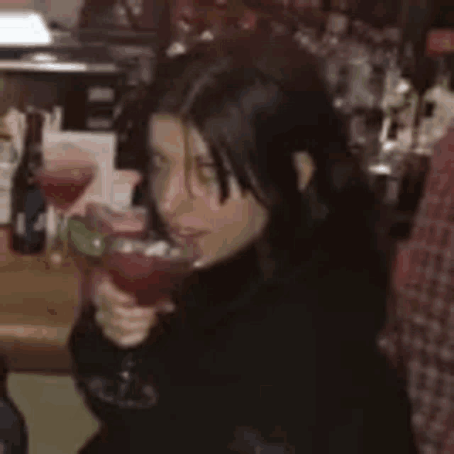 a woman is sitting at a table holding a martini glass .