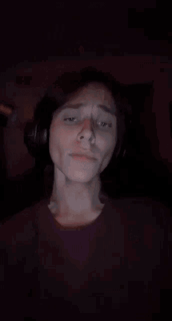 a woman wearing headphones makes a funny face with her eyes closed