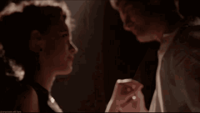 a man and a woman are holding hands and looking at each other .