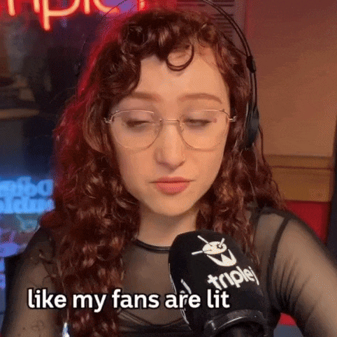 a woman wearing glasses and headphones says " like my fans are lit " in front of a microphone