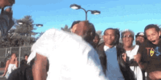 a group of people are standing around a man in a white shirt with a t on it