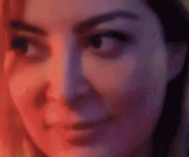 a close up of a woman 's face with a red and purple glow behind her .