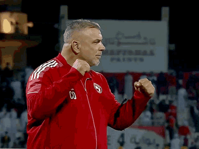 a man wearing a red adidas jacket with the number 60 on it