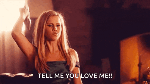 a woman in a green dress is holding a knife in her hand and saying `` tell me you love me '' .