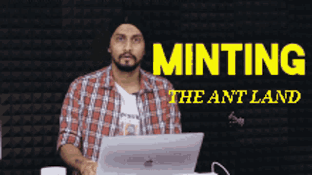 a man standing in front of a laptop with the words minting the ant land written above him