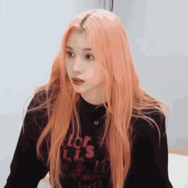 a girl with long pink hair is wearing a black sweater and a black sweater .
