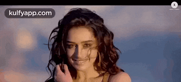a woman with curly hair is smiling at the camera .